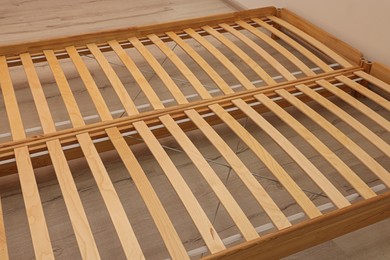 Photo of Wooden bed frame on floor in room, closeup view