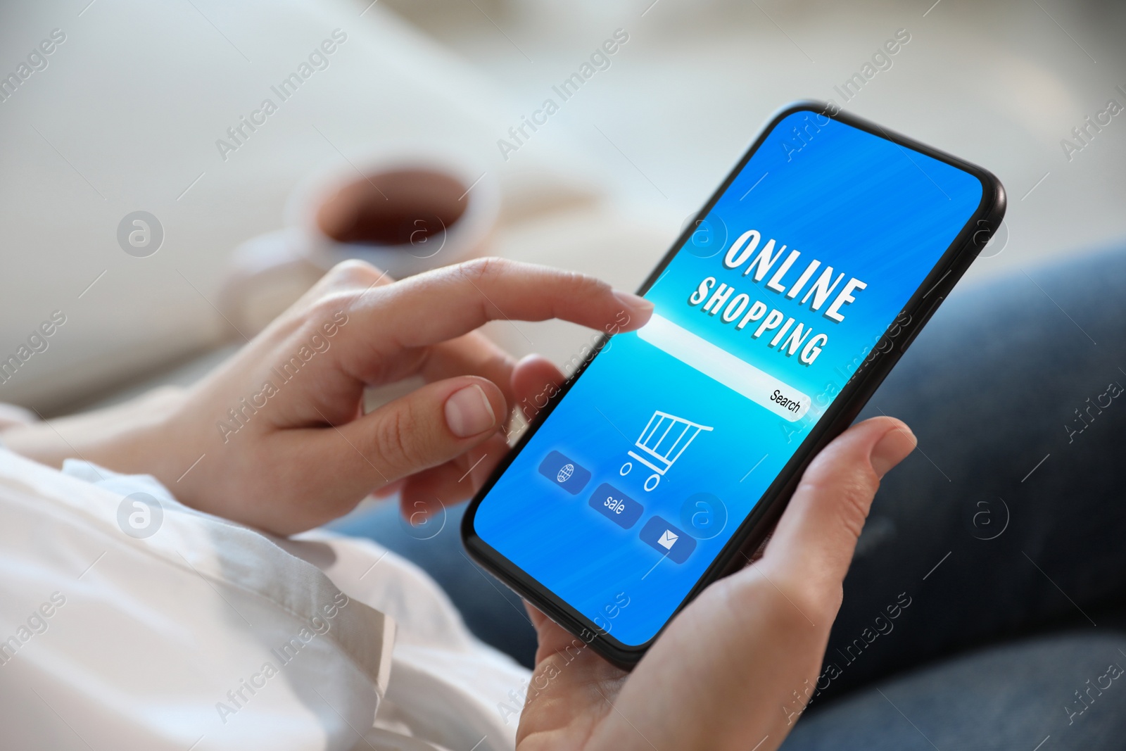 Image of Woman holding smartphone with online shopping website on screen indoors, closeup