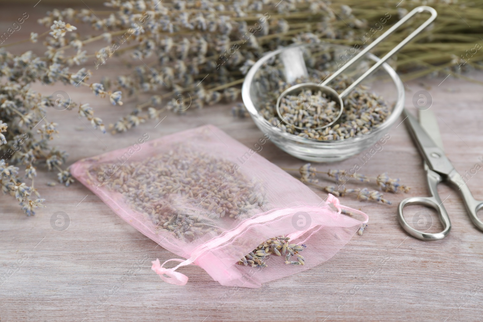 Photo of Scented sachet with dried lavender flowers and scissors on wooden table