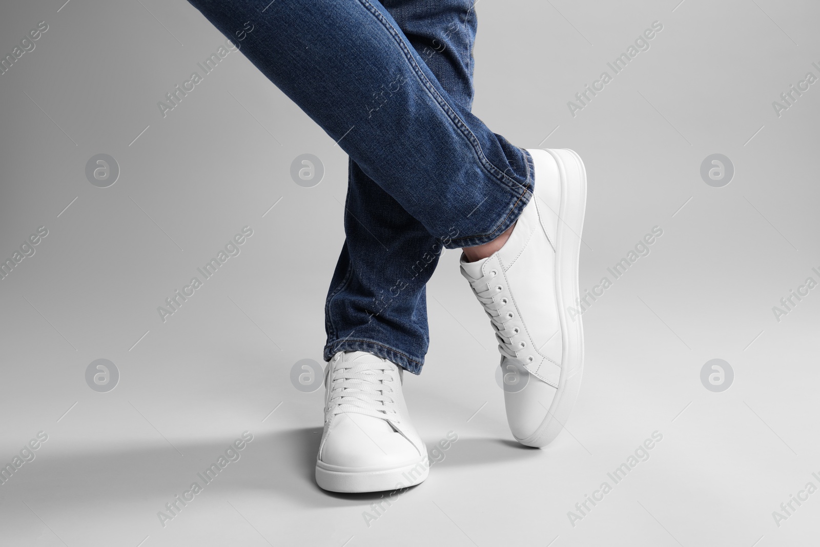 Photo of Man wearing stylish white sneakers on grey background, closeup