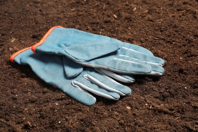Photo of Pair of protective gloves for gardening on soil