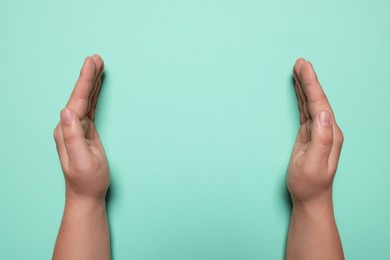 Photo of Woman holding on turquoise background, closeup of hands. Space for text