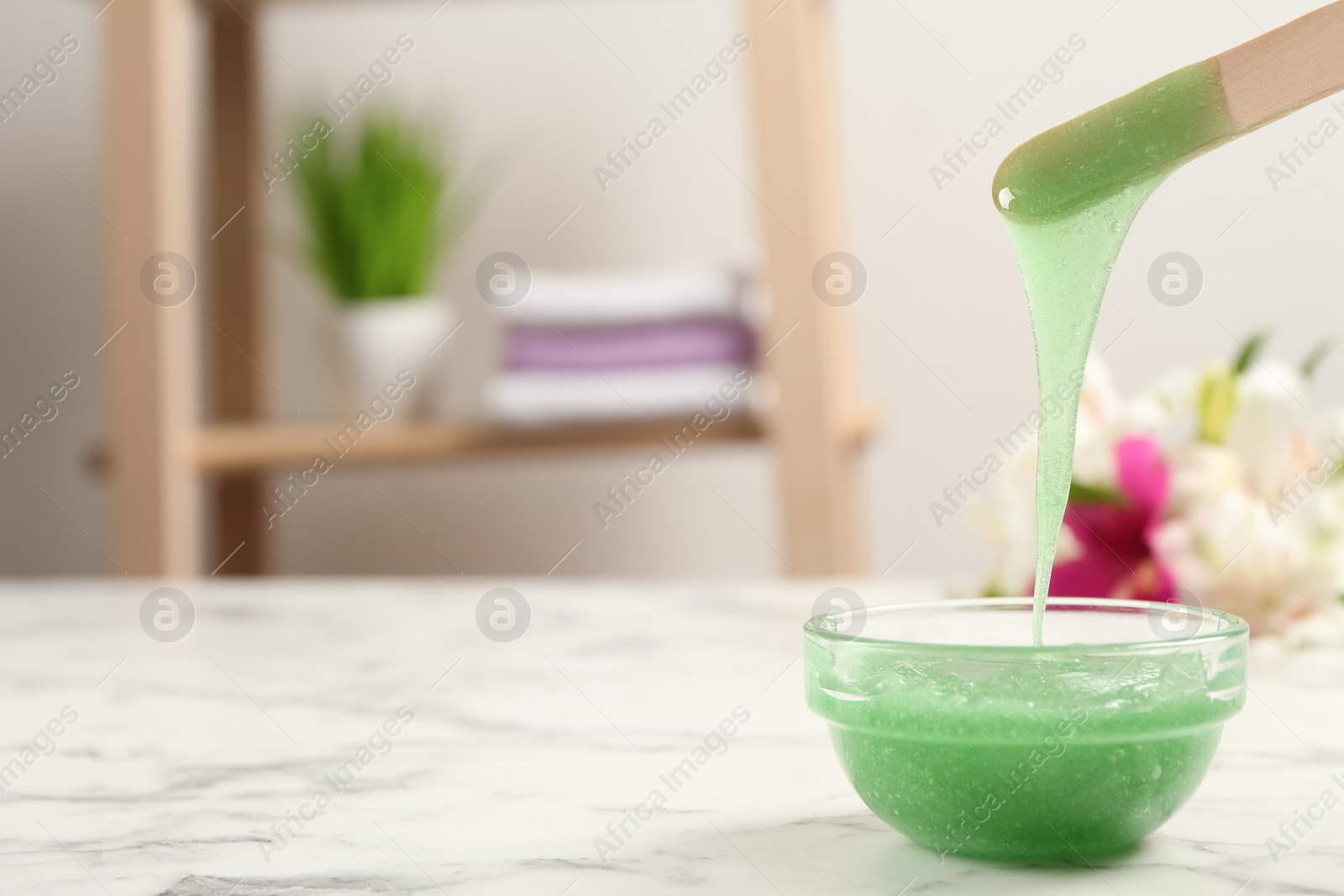 Photo of Spatula with wax on white marble table. Space for text