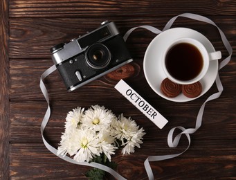 Flat lay composition with beautiful white chrysanthemum flowers and vintage camera on wooden table