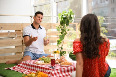 Photo of Happy couple with refreshing drinks imitating picnic at home