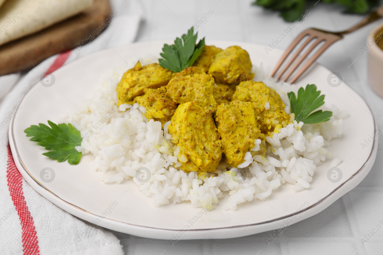 Photo of Delicious rice and chicken with curry sauce on white tiled table, closeup