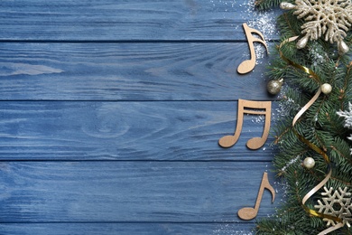 Photo of Fir tree branches with Christmas decor near decorative music notes and space for text on blue wooden background, flat lay