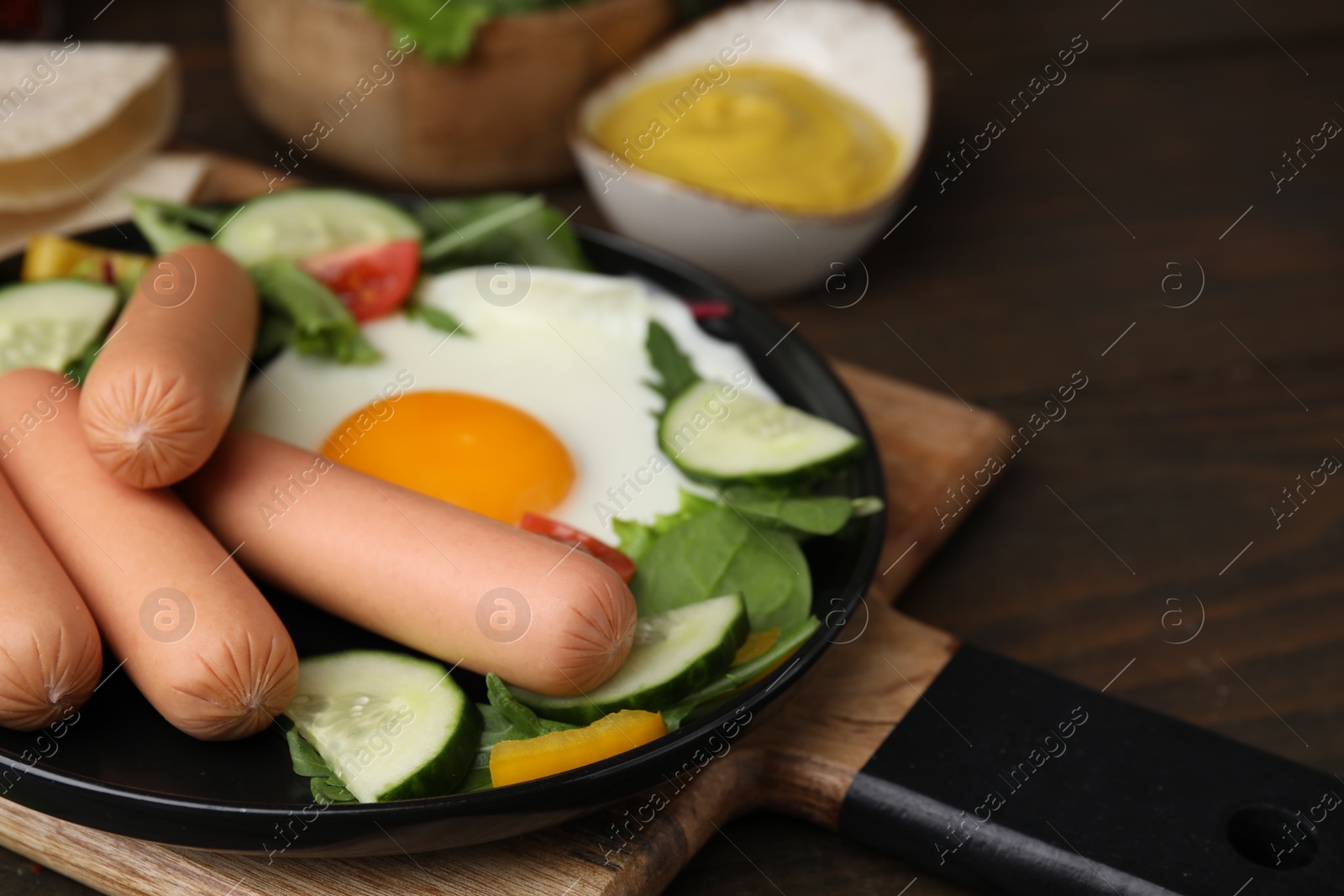 Photo of Delicious breakfast with boiled sausages and fried egg served on wooden table, closeup