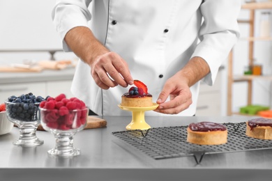 Photo of Male pastry chef preparing dessert at table in kitchen, closeup