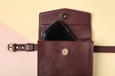 Stylish women's bag with smartphone on color background, top view