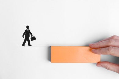 Woman holding wooden block near drawing of businessman walking on line, top view. Connection, relationships, help and deal concepts