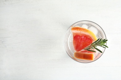 Glass of infused water with grapefruit slices on white table, top view. Space for text