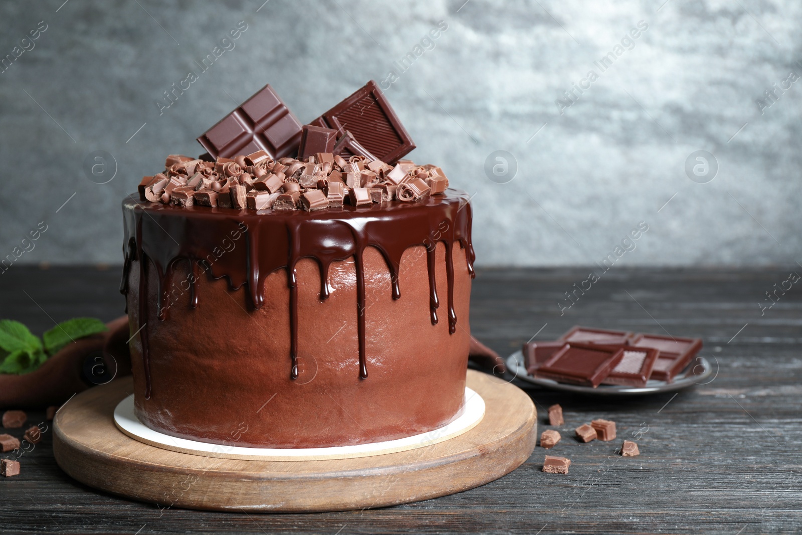 Photo of Freshly made delicious chocolate cake on black wooden table against grey background. Space for text