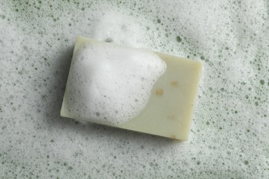 Photo of Soap and fluffy foam on green background, top view