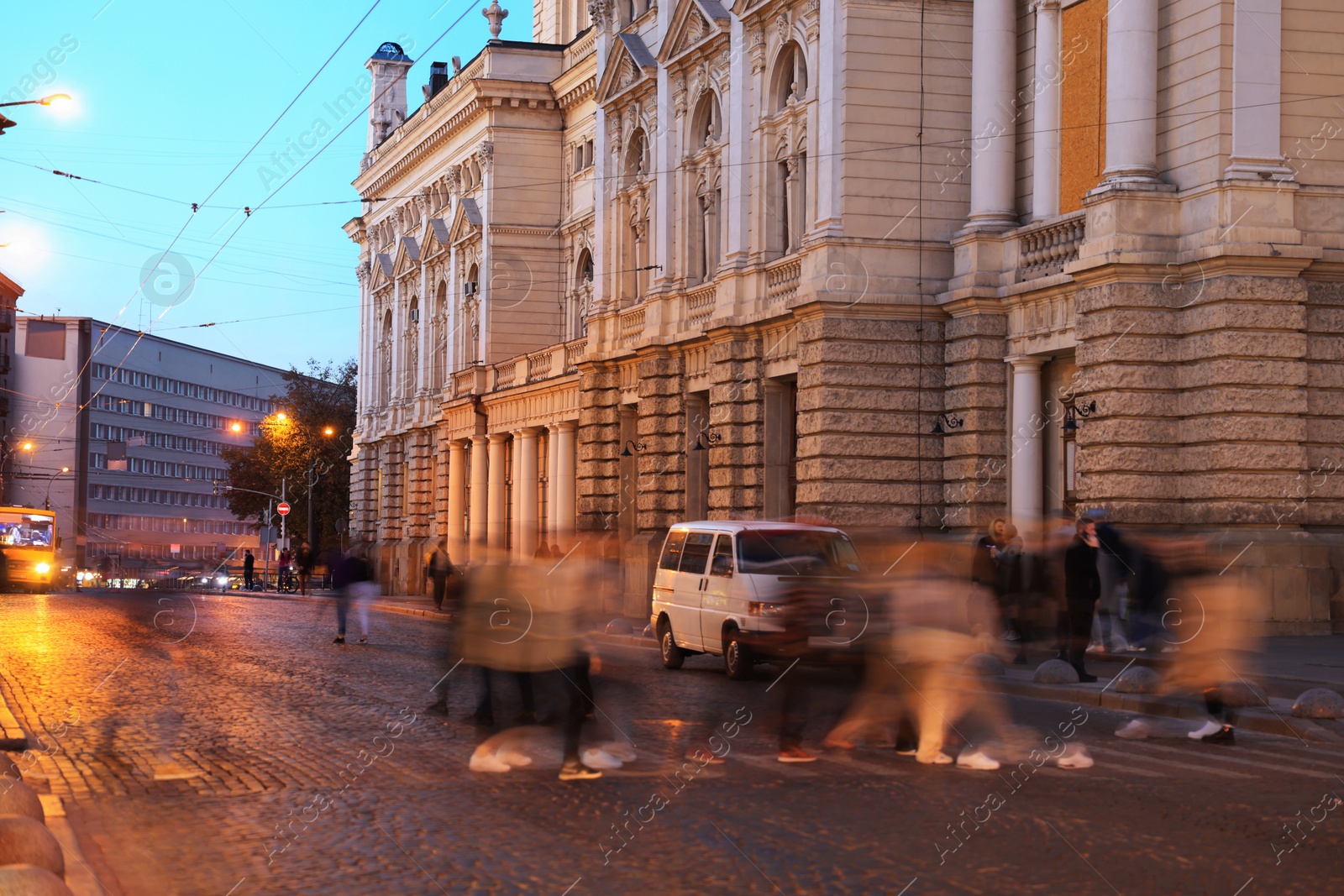 Photo of People crossing city street at evening, long exposure effect