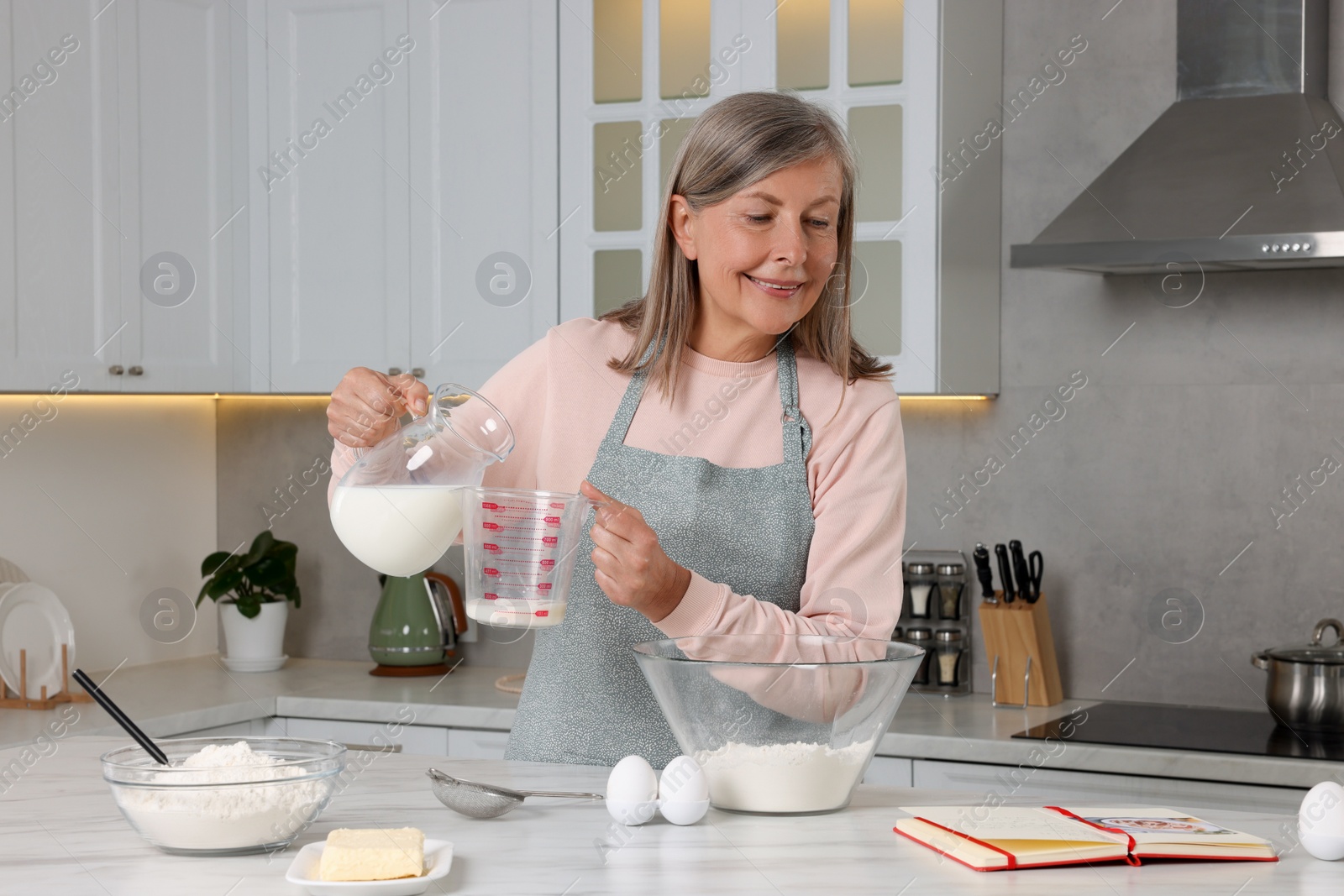 Photo of Senior woman with recipe book cooking in kitchen