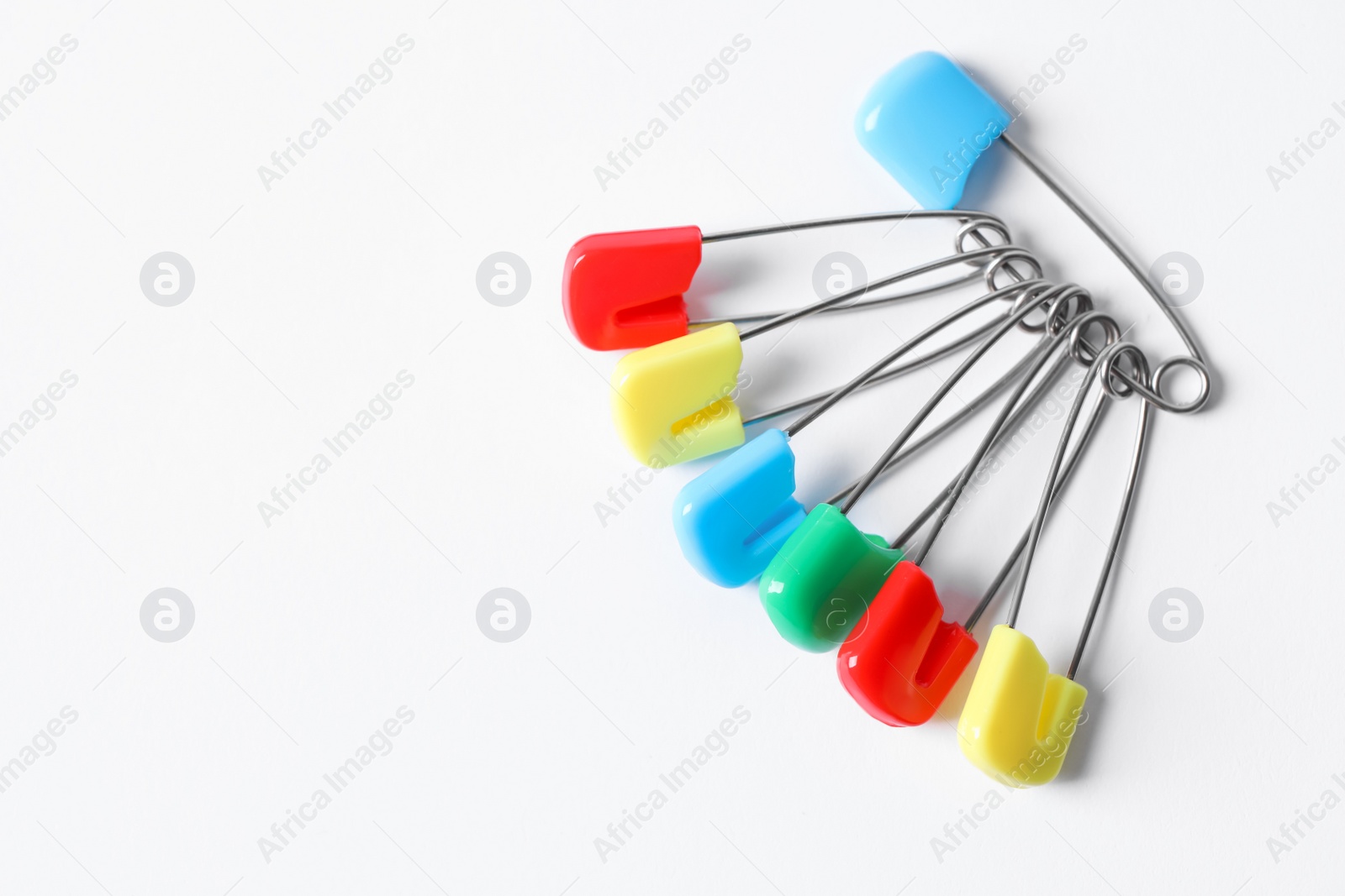 Photo of Colorful safety pins on white background, flat lay. Space for text
