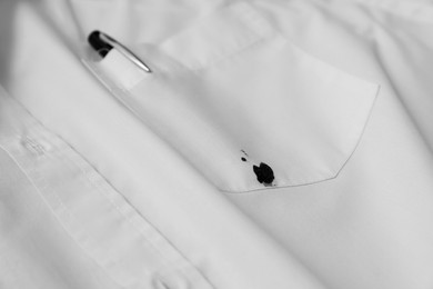 Photo of Pen and stain of black ink on white shirt, closeup