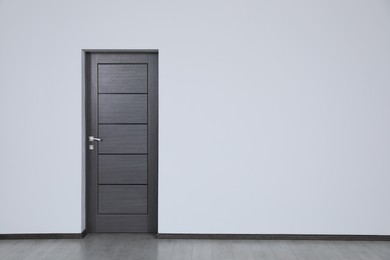 Photo of Dark wooden door in empty office, space for text. Interior design