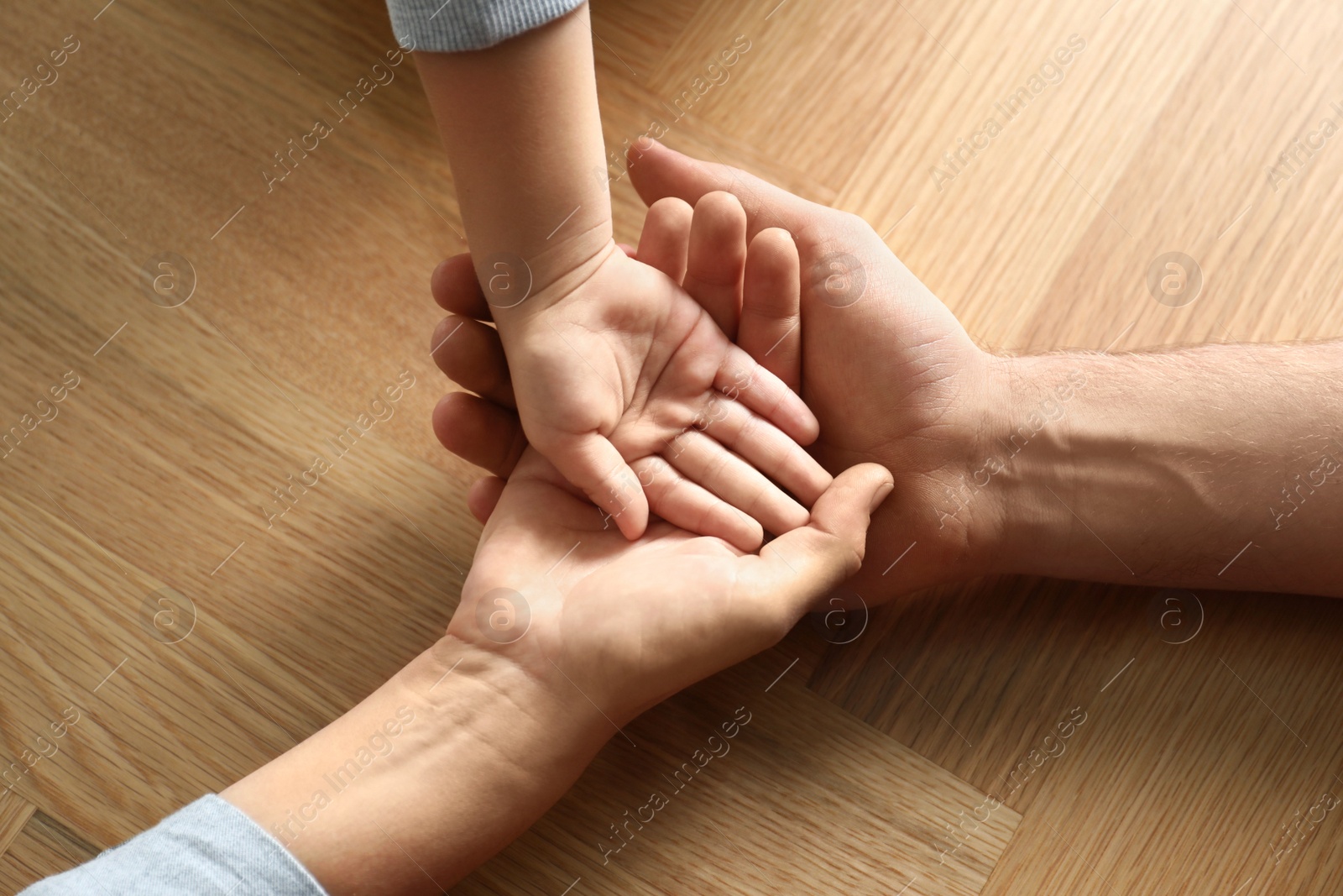 Photo of Happy family holding hands on wooden background, closeup