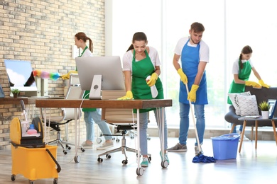 Photo of Team of professional janitors in uniform cleaning office