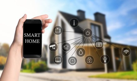 Image of Woman using phone application for controlling smart home outdoors, closeup
