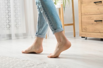 Photo of Woman stepping barefoot in room at home, closeup. Floor heating