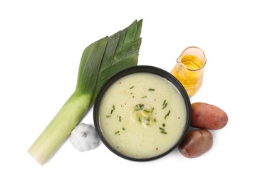 Photo of Bowl of tasty leek soup and ingredients isolated on white, top view