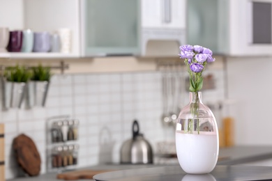 Vase with beautiful flowers on table in kitchen interior. Space for text