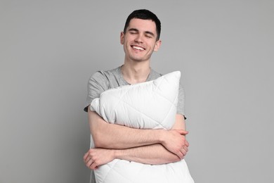 Photo of Happy man in pyjama holding pillow on grey background