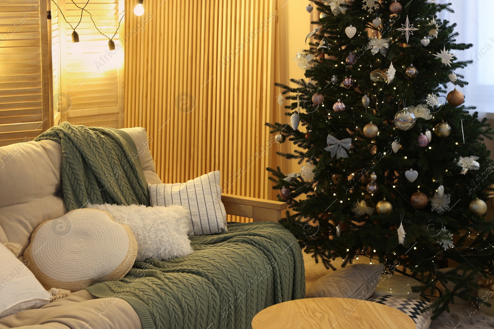 Photo of Comfortable sofa near Christmas tree in room