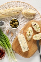 Photo of Tasty butter, bread and other ingredients on white wooden table, top view