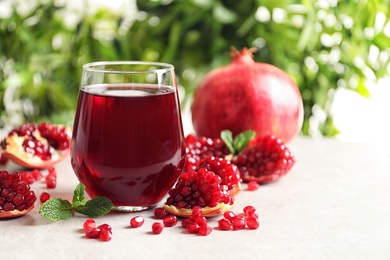 Photo of Composition with glass of fresh pomegranate juice on table. Space for text