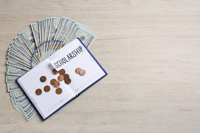 Photo of Paper with word Scholarship, notebook, banknotes and coins on wooden table, flat lay. Space for text