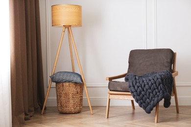 Photo of Knitted merino wool plaid on armchair in room