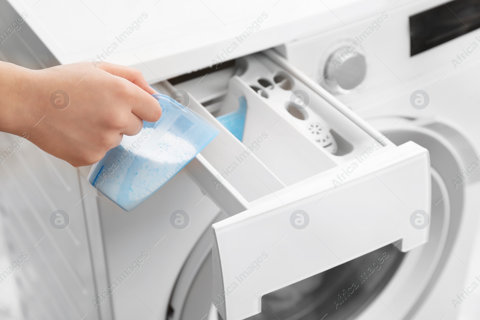 Photo of Woman pouring powder into drawer of washing machine, closeup. Laundry day