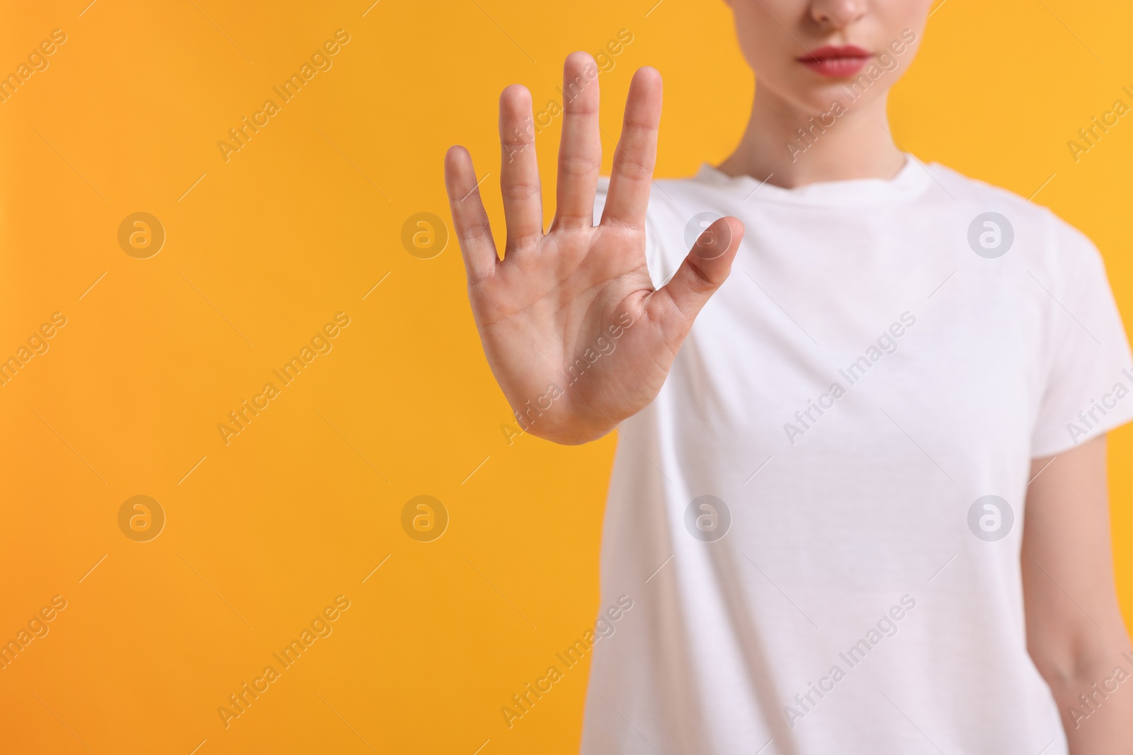 Photo of Woman showing stop gesture on yellow background, closeup. Space for text