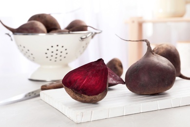 Photo of Wooden board with ripe beets on table