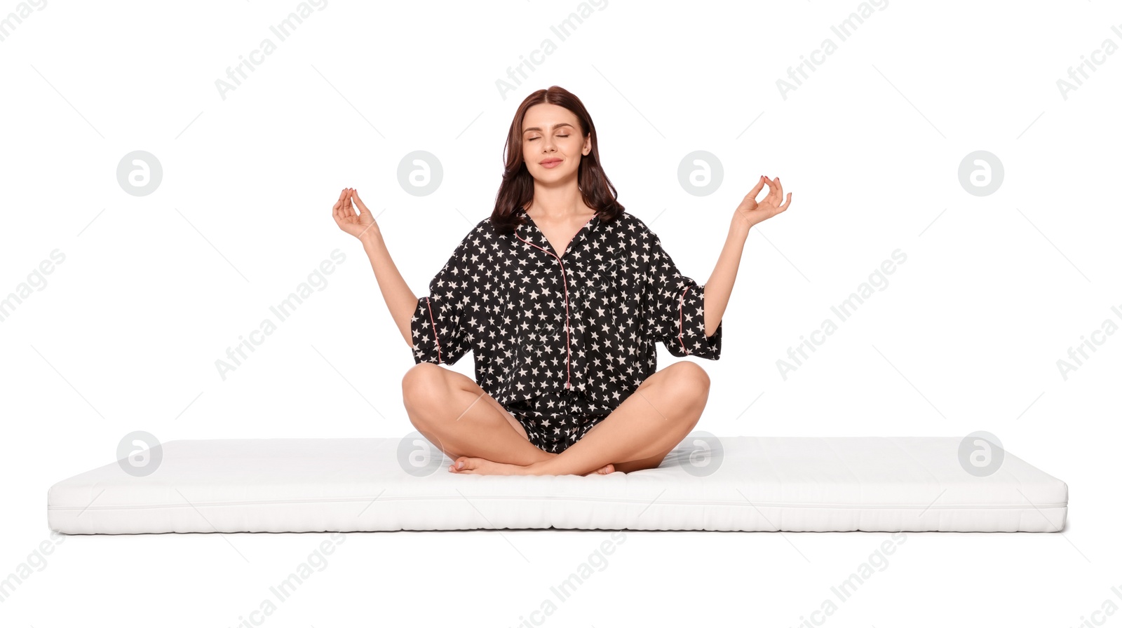 Photo of Young woman meditating on soft mattress against white background