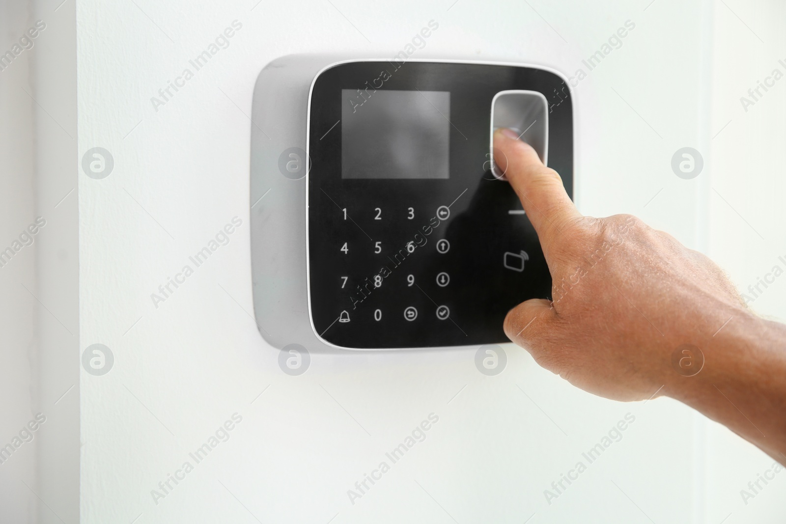 Photo of Mature man entering code on alarm system keypad indoors