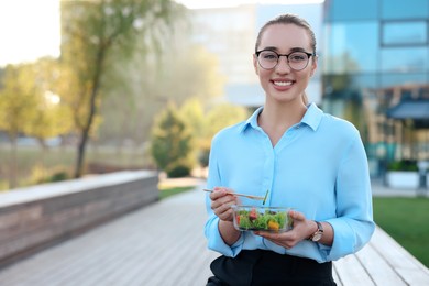 Portrait of smiling businesswoman with lunch box outdoors. Space for text