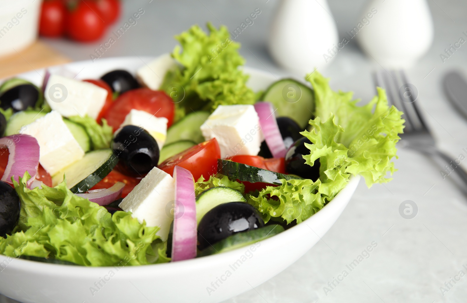 Photo of Tasty fresh Greek salad on grey table, closeup