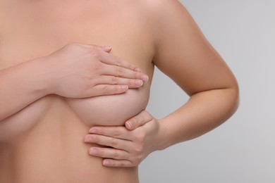 Photo of Mammology. Naked woman doing breast self-examination on light grey background, closeup