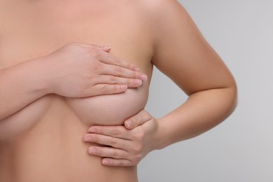 Mammology. Naked woman doing breast self-examination on light grey background, closeup