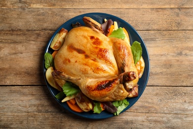 Photo of Delicious cooked turkey with garnish on wooden table, top view. Thanksgiving Day celebration