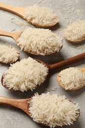 Photo of Raw basmati rice in spoons on grey table