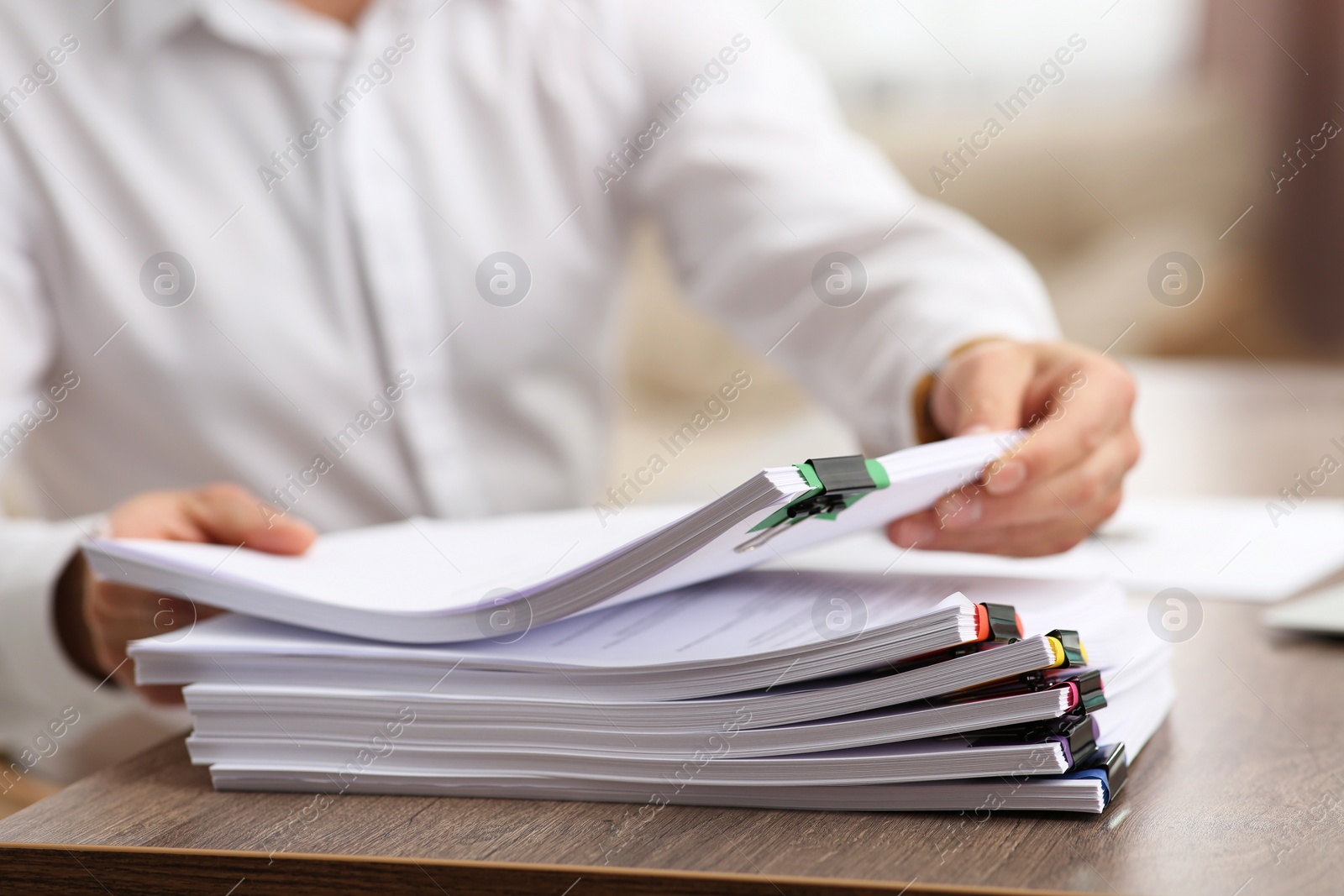 Photo of Man working with documents at wooden table in office, closeup