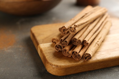 Photo of Aromatic cinnamon sticks on grey table, closeup. Space for text