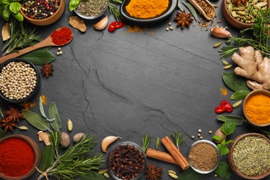Frame of different herbs and spices on black table, flat lay. Space for text