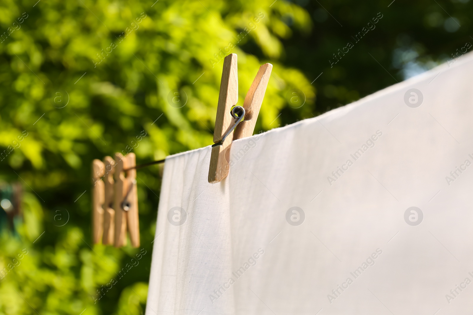 Photo of Washing line with clean laundry and clothespins outdoors, closeup